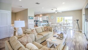 A spacious living area with a sofa set, a dining table, and a kitchen in the background. - Direct Oceanfront Private Paradise - Pool/Spa/Dock (Marathon)