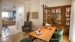 A dining area with a wooden table, four green chairs, and a glass cabinet with dishes. - 3 bedroom apt next to Syntagma with Acropolis view, Luxury Apartment (Athens)