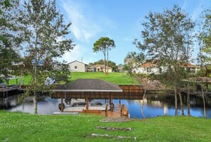 A serene lakeside property with a wooden dock, a covered seating area, and a grassy lawn. - Fully updated canal front home with access to Lake June (Lake Placid)