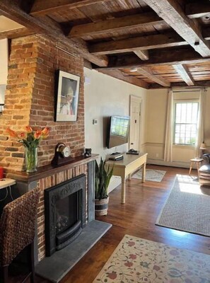 Cozy living room with a brick fireplace, television, and comfortable seating area.