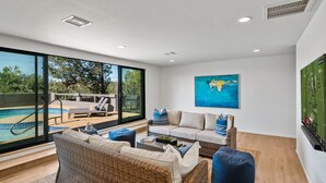 A spacious living area with wicker furniture, a pool view, and a large painting. - 5BR/Heated Pool/Hot Tub/Fire Pit/Views/Sauna/Pets OK (Sedona)