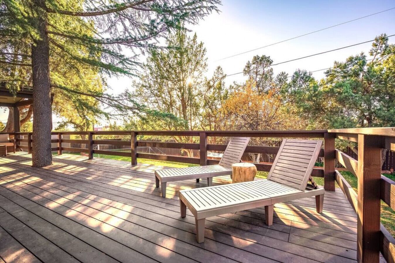 Una terraza de madera con dos sillones de descanso y una barandilla de madera.