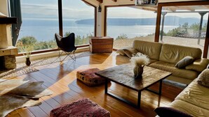 Amplia sala de estar con un gran ventanal que ofrece una vista panorámica de un lago y montañas.