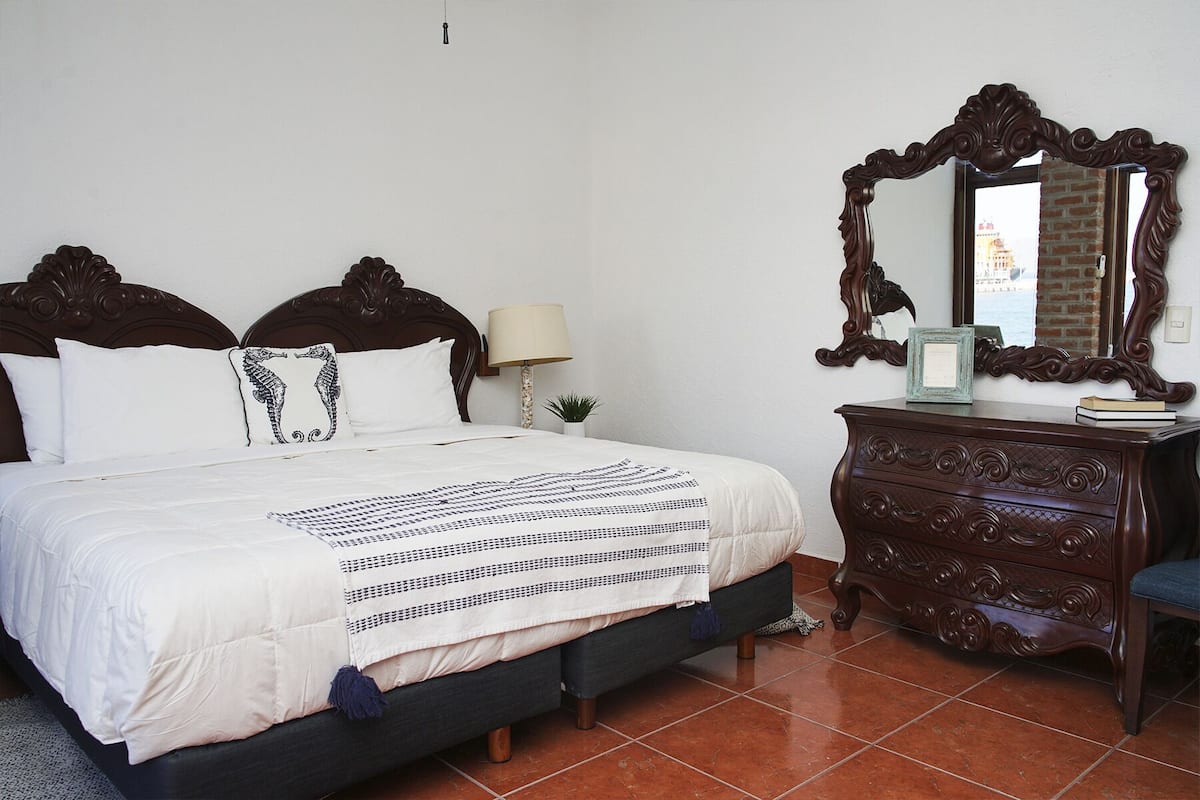 Une chambre à coucher avec un grand lit, une commode, un miroir et une lampe.