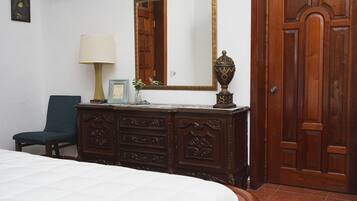 Un dormitorio con cama, cómoda, silla, espejo y puerta.