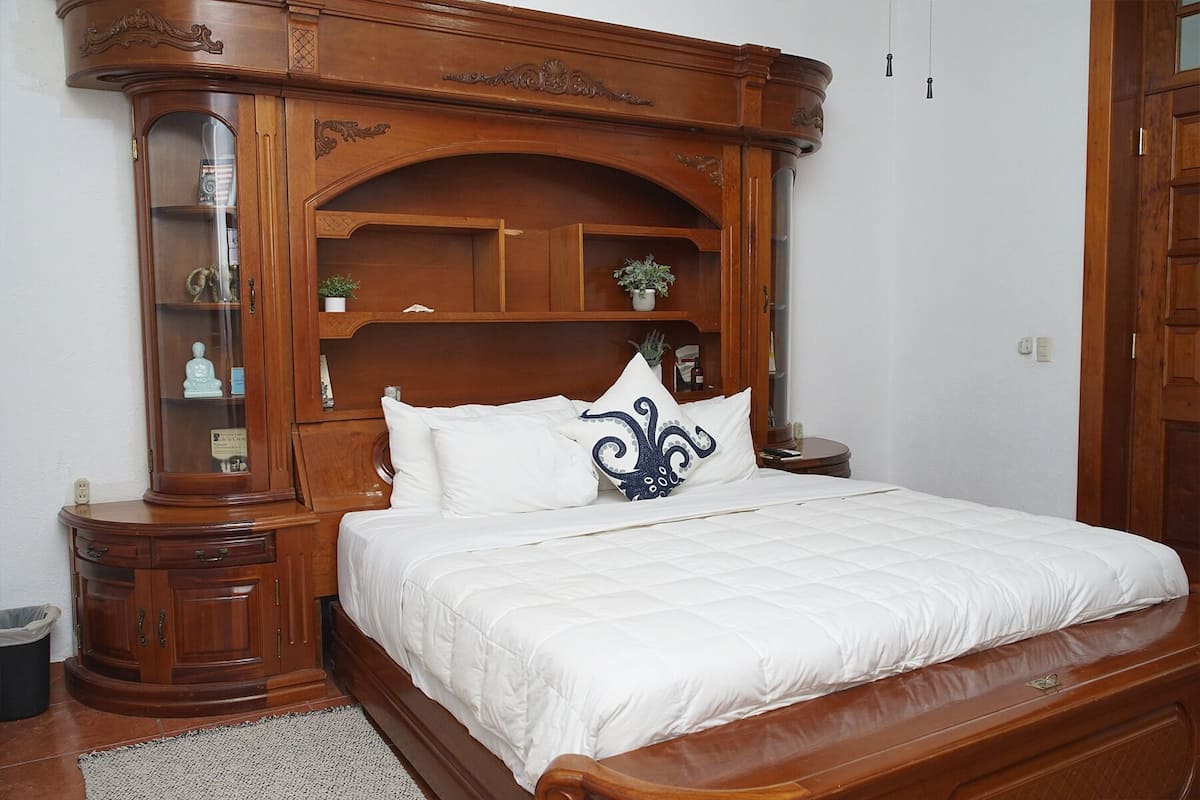 Une chambre à coucher avec une tête de lit en bois, un lit avec une literie blanche et une petite table de chevet.