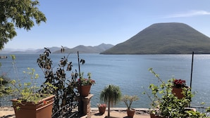 Een terras met plantenbakken met uitzicht op een rustig meer en verre bergen.
