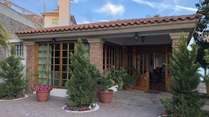 Een huis met twee verdiepingen, een pannendak, een bakstenen gevel en een overdekte veranda met potplanten.