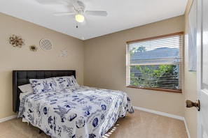 A bedroom with a bed, a ceiling fan, and a window with blinds.