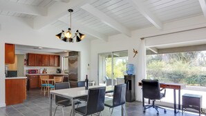 Une cuisine moderne avec des meubles en bois, un coin repas comprenant une table et des chaises, et une grande fenêtre offrant une vue sur l’extérieur.