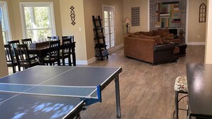 Un'ampia zona giorno con tavolo da ping pong, divano e tavolo da pranzo con sedie.