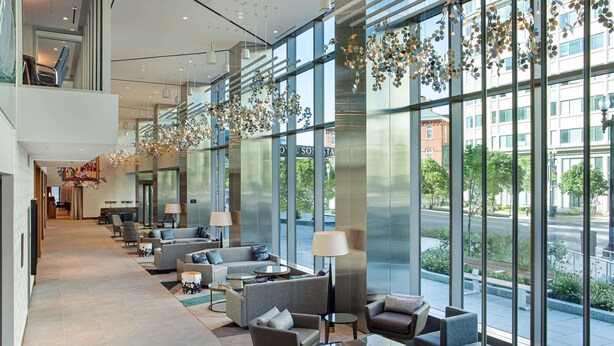 Un hall espacioso con asientos modernos, ventanas amplias y decoraciones florales colgantes.