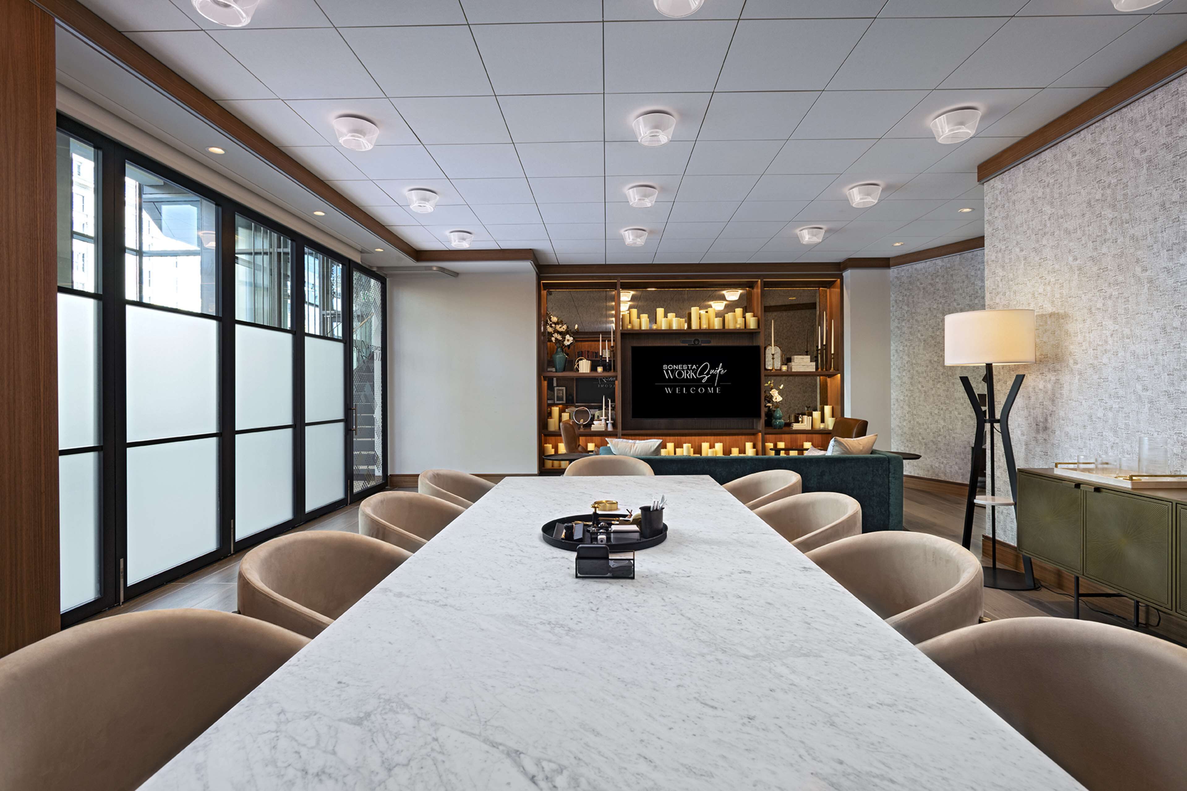 A modern conference room with a marble table, beige chairs, and a large window.