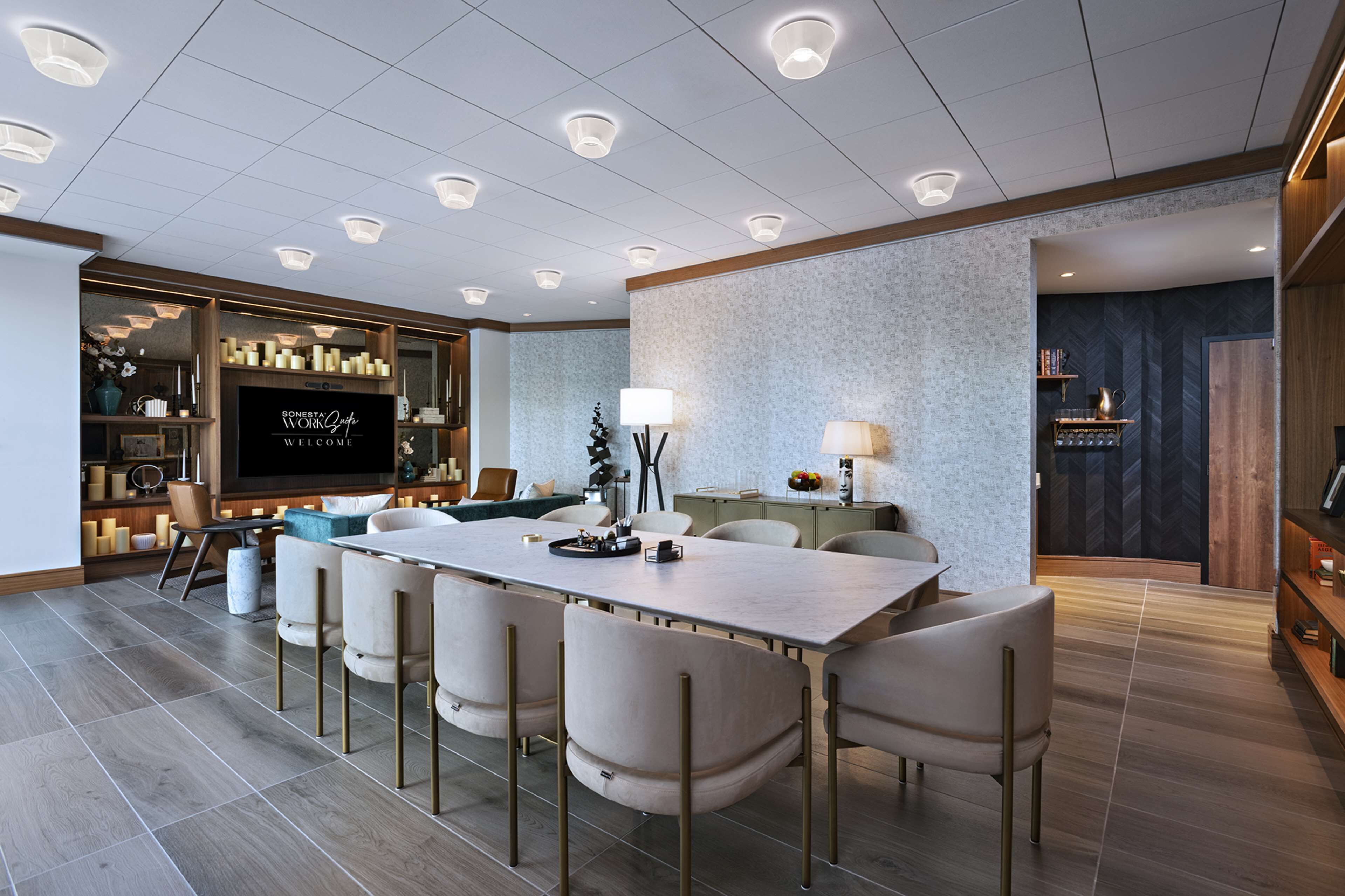 Een moderne hotelkamer met een grote eettafel, comfortabele zithoek, een flatscreen televisie en een gezellige zithoek met open haard.