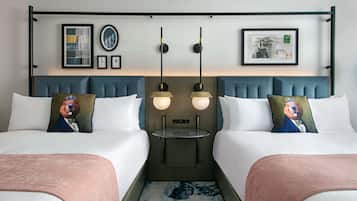 Habitación de hotel con dos camas, cabecera con estante integrado y obra de arte en la pared.