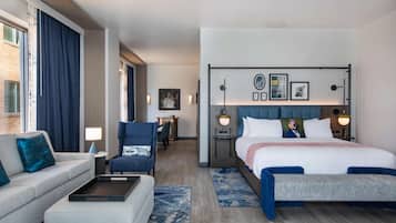 Una habitación de hotel con una cama, un sofá, una silla, un escritorio y una mesita.