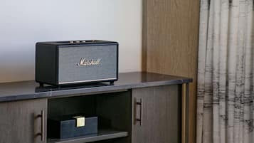 Un televisor de pantalla plana montado en una pared sobre un mueble de entretenimiento de madera con un altavoz Marshall.