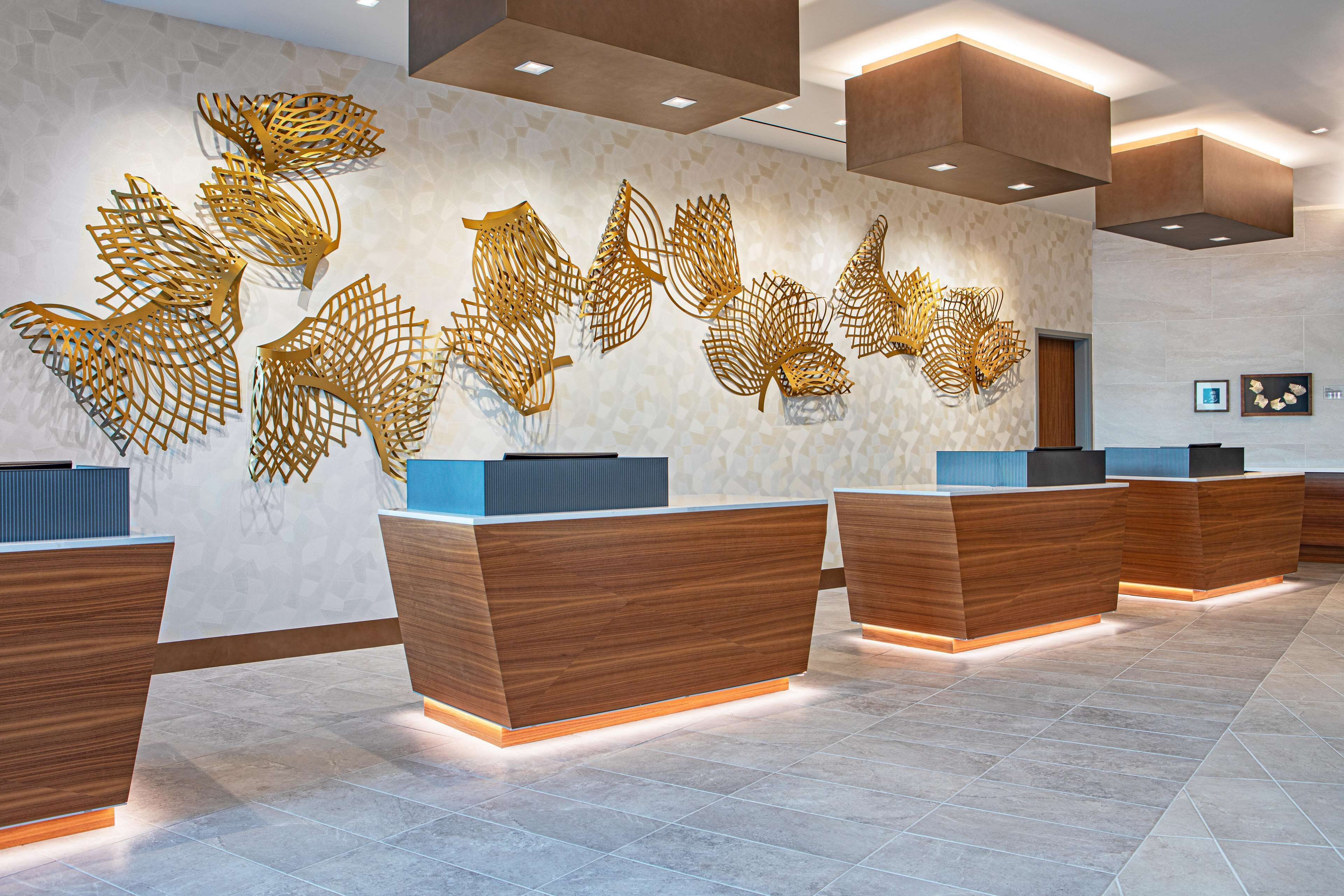 A reception area with wooden reception desks, a patterned wall, and abstract wall art.