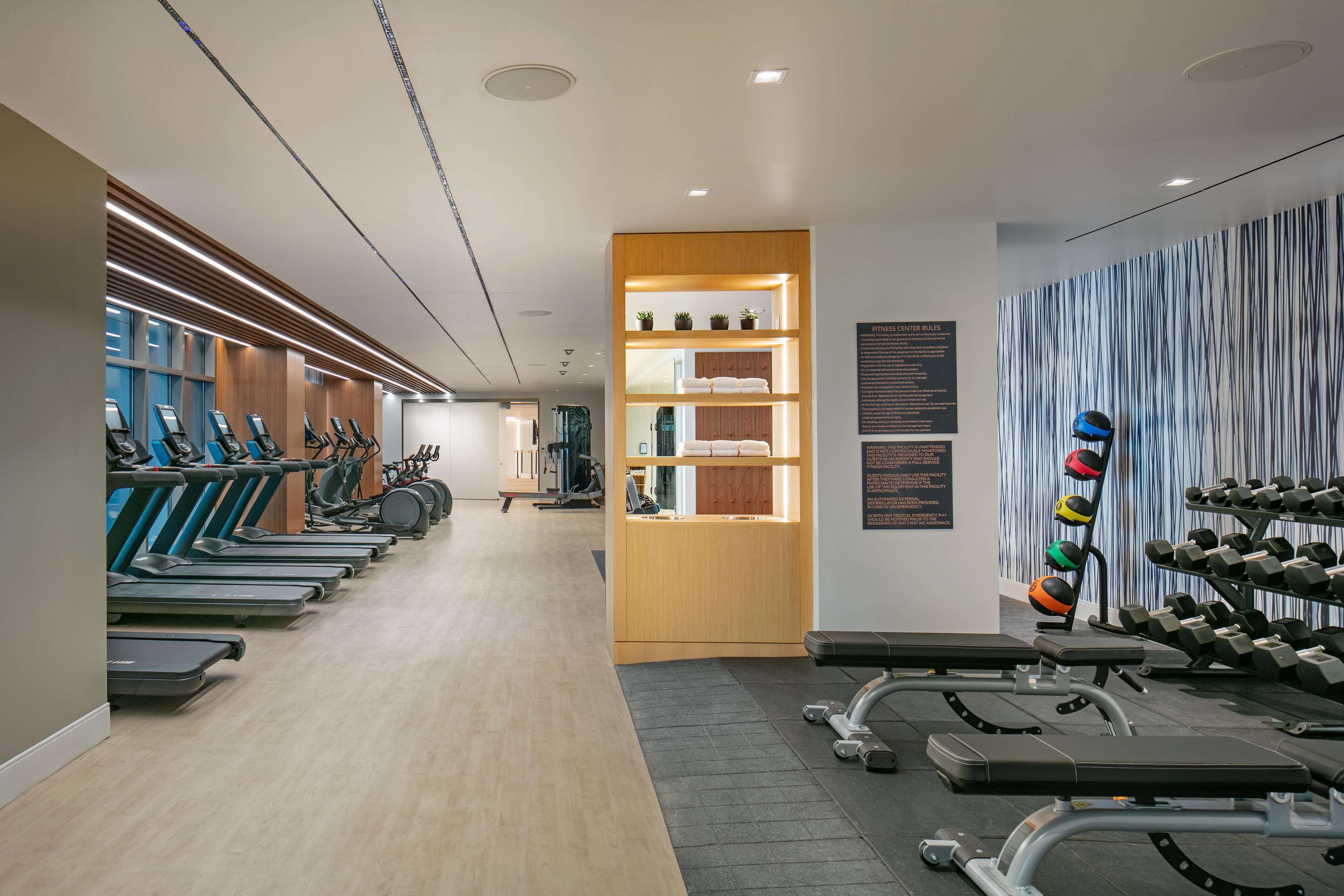 Une salle de sport équipée de tapis de course, de bancs de musculation et d’haltères.