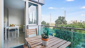 Uma varanda com uma mesa de madeira, um cacto em vaso e vista para a cidade.