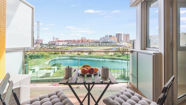 Ein Balkon mit Tisch, Stühlen und Blick auf Stadt und Fluss.