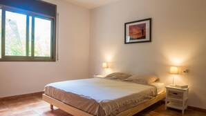Une chambre à coucher avec un lit en bois, deux tables de chevet avec des lampes, une fenêtre et un tableau encadré au mur.