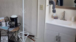 A bathroom with a white sink, a mirror, and a coat rack. - Cabin 21 - Bicycle Retreat (Helena)