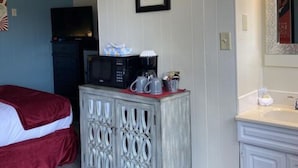 Una habitación de hotel con una cama, un tocador, un microondas y un lavamanos.