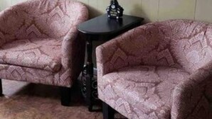 Dos sillones estampados y una pequeña mesa en una habitación con un letrero que dice "Hibernation Station".