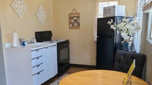 Un espacio habitable compacto con kitchenette, una mesa de comedor y una zona de estar.