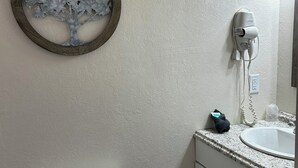 Une salle de bain équipée de toilettes, d’un lavabo et d’un sèche-cheveux fixé au mur.