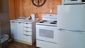 Une cuisine avec des lambris en bois, un évier, une cuisinière et un four à micro-ondes.