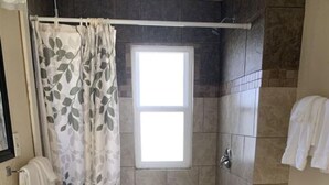 A bathroom with a shower, toilet, sink, and a window. - Suite 34- Victorian Suite (Helena)