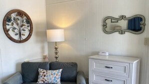 A living room with a grey sofa, a coffee table, a white dresser, a lamp, and a decorative mirror. - Suites 34 & 35 - Victorian Suites (Helena)