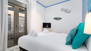 Quarto de hotel com uma cama, televisão e vista através de uma porta de vidro.