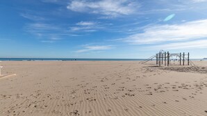 Uma praia com pegadas, um parquinho e o oceano ao fundo.