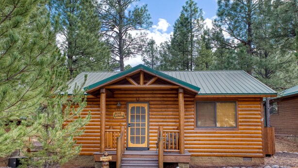 Una cabaña de troncos con una entrada acogedora, un porche y un letrero que dice "Bear Haven".