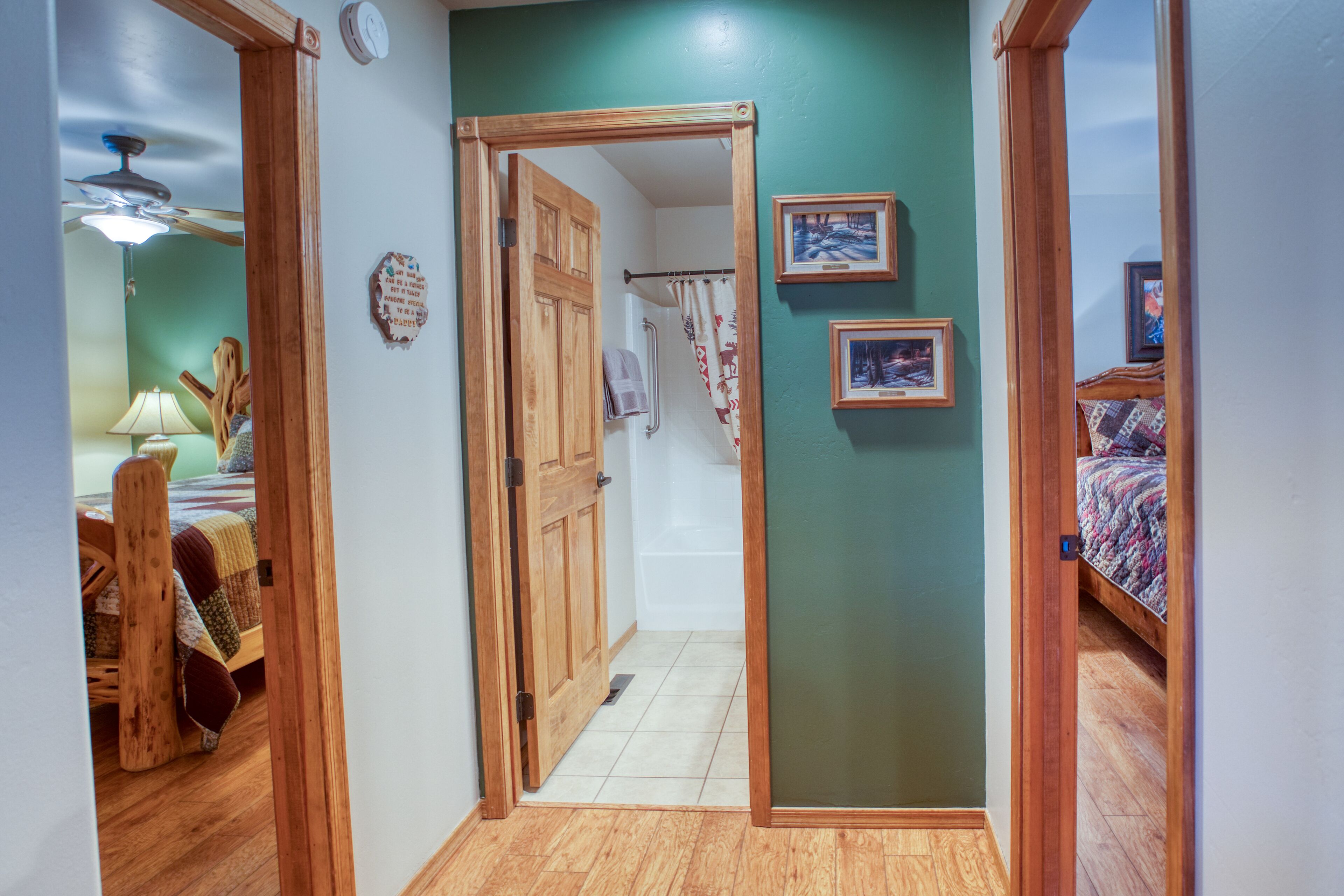 A hallway with wooden flooring, a wooden door, and a bed with a colorful quilt.