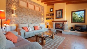 A cozy living room with a stone wall, a fireplace, a sofa, and a coffee table. - La Salve d'alt villa with private pool (Pollensa)