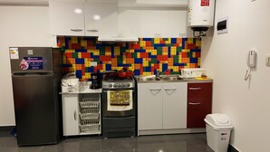 Eine Küche mit einer farbenfrohen LEGO-Wand, einem Kühlschrank, einem Backofen und einem Spülbecken.