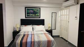 Ein Hotelzimmer mit einem Bett, zwei Nachttischen mit Lampen, einem großen Spiegel, einem Kleiderschrank und einer Klimaanlage.