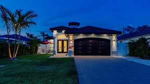 Une maison moderne avec un garage, une pelouse bien entretenue et des palmiers.