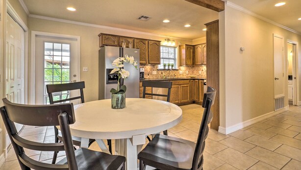 A kitchen with wooden cabinets, a refrigerator, and a dining table with chairs.