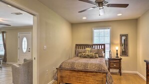 A bedroom with a bed, a ceiling fan, a nightstand, and a window.
