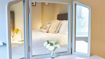 A room with a bed, a mirror cabinet, and a vase with flowers.