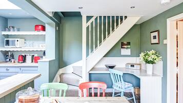 A kitchen with a dining area, a staircase, and a small table with a cake and utensils.