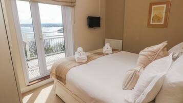 Habitación de hotel con cama, televisor, un cuadro y balcón con vistas.