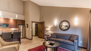 A modern living room with a sofa, coffee table, and a kitchen area with a refrigerator and microwave. - Ocean Front Resort - 1 Bedroom Suite (Parksville)