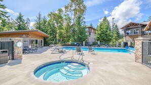 A pool area with a hot tub, lounge chairs, and a building with a stone facade. - Ocean Front Resort - 1 Bedroom Suite (Parksville)