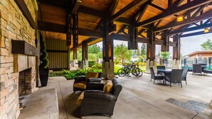 A covered patio with wicker furniture, a stone fireplace, and bicycles in the background. - Ocean Front Resort - 1 Bedroom Suite (Parksville)